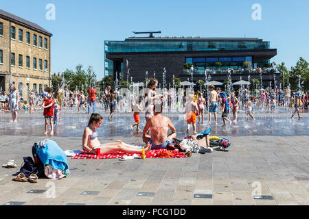 Familien und Kinder kühlen sich in den Brunnen des Granary Square ab, wenn die Temperaturen steigen, King's Cross, London, Großbritannien Stockfoto
