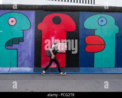 Berlin, Deutschland. 2 Aug, 2018. Eine Frau gesehen zu Fuß neben die Reste der Mauer, die von Künstlern aus aller Welt im Jahre 1990 gemalt wurden. Berliner Mauer wurde von Soldaten in der Bernauer Straße in die Stadt nach der Ideologie Teilen gebaut und auch geteilte Familien, Freunde und Nachbarn. Es stand bis 9. November 1989 als Barriere zwischen Ost und West, Diktatur und Demokratie. Credit: Jana Cavojska/SOPA Images/ZUMA Draht/Alamy leben Nachrichten Stockfoto