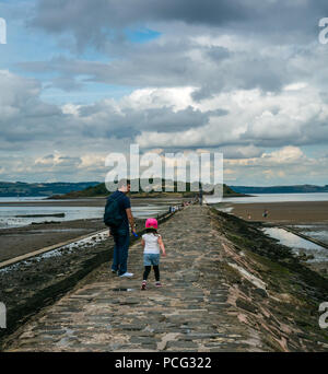 Cramond, Edinburgh, Schottland, Großbritannien, 2. August 2018. Ein Vater und ein Kind gehen auf dem Gezeitendamm nach Cramond Island Stockfoto