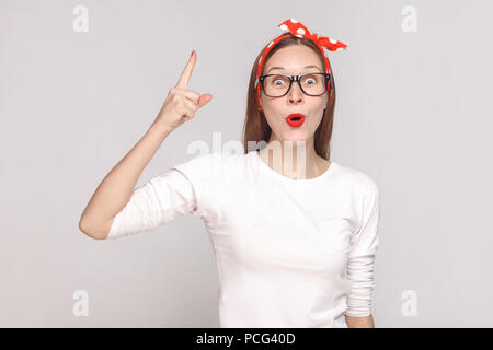 Wow. Ich habe eine Idee. Porträt der Schönen emotionalen junge Frau im weißen T-Shirt mit Sommersprossen, schwarze Brille, rote Lippen und Kopfband. indoor Studio Stockfoto