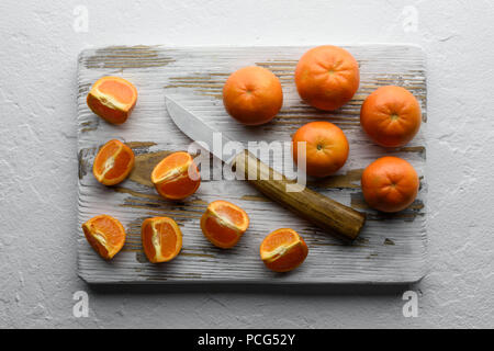 Mandarinen und Messer auf Holzbrett Stockfoto