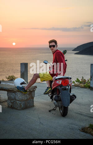 Portrait von Biker auf dem Motorrad, in der Nähe des Strandes hängen. Schöner Mann sitzen auf dem Motorrad, Sonnenuntergang. Stockfoto