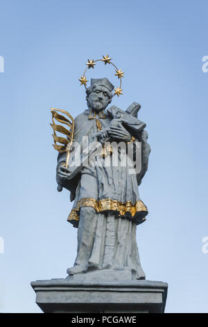 Statue des Hl. Johannes von Nepomuk in Olesno, Polen mit gold Elemente, die Palme des Martyriums, Halo von fünf Sternen, Bademäntel und Kruzifix Kreuz mit Jesus. Stockfoto