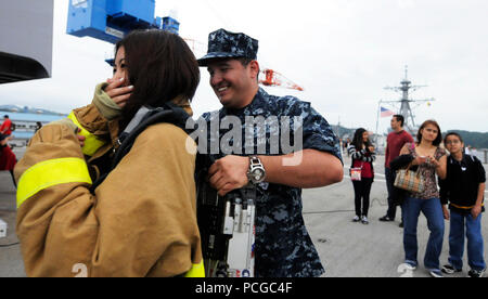 Petty Officer 3. Klasse David Hyndman, machinist mate, hilft ein Gast an Bord des US-amerikanischen 7 Flotte Befehl Schiff USS Blue Ridge Kleid in eine Brandbekämpfung Ensemble, wie das Schiff unterwegs für eine Kreuzfahrt nach Tokio geht. Freunde und Familie von Blue Ridge und US 7 Flotte personal Matrosen, sowie Seeleute aus dem Japan Maritime Verteidigung-kraft waren an Bord für die 4-Stunde im Gange, der Empfohlene damage control Ausrüstung Demonstrationen und eine Leistung durch die USA 7 Flotte Band eingeladen. Stockfoto