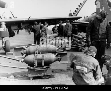 USS philippinischen Meer (CV-47): 250-Pfund Bomben unter den Flügeln eines Douglas AD Skyraider von Attack Squadron 65 geladen werden, während der weg von der koreanischen Küste, 21. Mai 1951. Ein Warenkorb 5-Zoll-Raketen und einen zweiten Wagen mit 250-Pfund Bomben sind ebenfalls vorhanden. Stockfoto