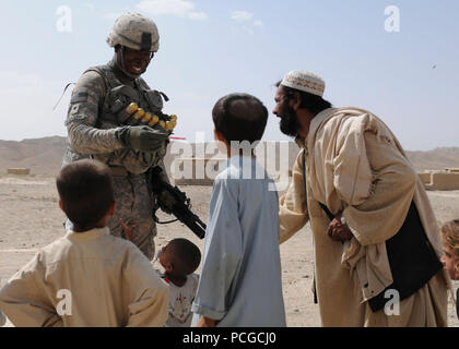 Us-Armee SPC. Denoah Randolph, Mitglied der Border Management Task Force, gibt Süßigkeiten an die Kinder während einer Tournee ein Dorf in der Nähe der afghanischen Grenze Patrouille Außenposten in Shurabak Bezirk. Randolph und sein Team begleitet Col. Ghuzai Sharif, Commander, 3. Zone, Afghan Border Patrol, bei einem Besuch der Vorposten und Dorf Truppe und das Dorf Bedürfnisse zu ermitteln. Der afghanischen Grenze Patrouille hat mit der ISAF-task force zusammengeschlossen, um Truppen zu erhöhen und lernen Taktiken zur Sicherung der afghanischen Grenze. Stockfoto