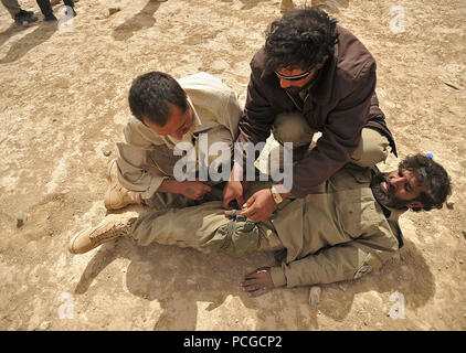 Afghanische Polizei Rekruten Praxis und Anwendung blutsperregeräte auf anderen Rekruten während einer bekämpfen Medical Class in Nawbahar Bezirk, Zabul Province, Afghanistan, am 18. März. Die Klasse ist Teil eines 3-wöchigen Kurs lehrt, dass die ALP Kandidaten grundlegende Polizeiarbeit Verfahren, den Umgang mit Waffen und anderen notwendigen Fähigkeiten afghanische Bürger zu schützen und zu verteidigen. Stockfoto