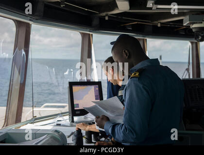 Von GUINEA (April 2, 2014) - einem ghanaischen Sailor, Links, und Oberstleutnant Jeffrey Deitel, der US-Küstenwache Strafverfolgungsbehörden Loslösung zugewiesen, beide begannen an Bord der Military Sealift Command joint high-speed Schiff USNS Speerspitze (Jhsv 1) Überprüfen Sie Dokumente auf einen vermuteten illegalen Fischereifahrzeuge als Teil der USA und Ghana Marine kombiniert maritimen Strafverfolgung Betrieb unter den afrikanischen Maritime Strafverfolgung Partnerschaft Programm. Stockfoto