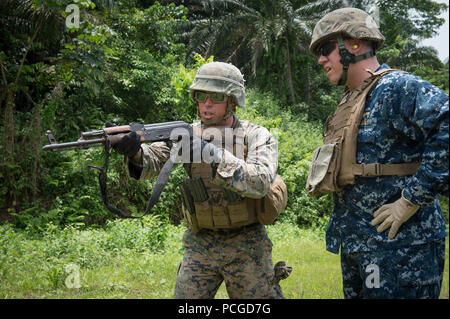 ISSONGO, Kamerun (14. März 2015) Marine Sgt. Benjamin Sheely, Links, gibt Anweisungen zum 6. US-Flotte stellvertretender Kommandeur der Adm. Tom Reck auf, wie man Feuer ein AK-47-Sturmgewehr während auf einem Schießplatz in Afrika Partnerschaft Stationon März 14, 2015, in Issongo, Kamerun. , Afrika Partnerschaft Station, eine internationale Zusammenarbeit capacity-building-Programm wird in Verbindung mit einer geplanten Bereitstellung durch gemeinsame hohe Militärs Sealift Command durchgeführt-Schiff USNS Speerspitze (Jhsv 1). Stockfoto