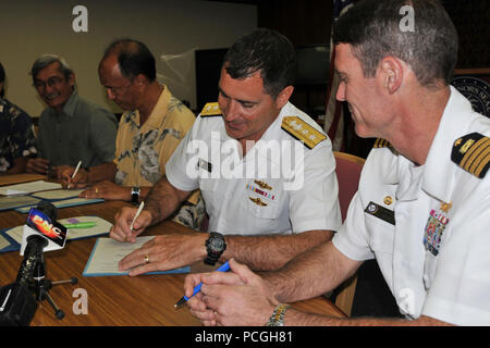 Hintere Adm. Paul Bushong, Mitte, Kommandant der gemeinsamen Region Marianen, unterzeichnet ein Memorandum of Understanding mit der konsolidierten Kommission auf Dienstprogramme, Guam Wasserwerk Autorität und Guam Power Authority am Ricardo J. Bordallo Governor's Komplex in Hagatna, Guam. Die US-Marine ist Lösungen vereinbaren Zusammenarbeit Dienstprogramme auf Guam in der Vorbereitung für die Marine Umzug von Okinawa, Japan zu verbessern. Stockfoto