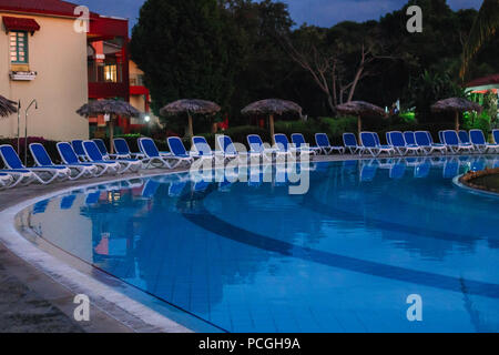 Gruppe Reihe mit vielen leeren Stühlen stehen rund um den Pool mit blauen Wasser am Abend Nacht, großes Hotel, das Gebiet der Gemeinschaft Stockfoto