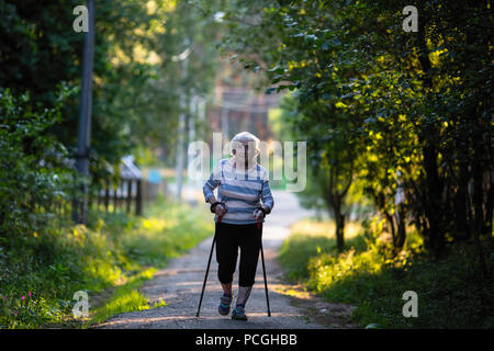 Nordic Walking. Ältere Frau mit Skistöcken ist auf der Straße. (90 Jahre alt) Stockfoto