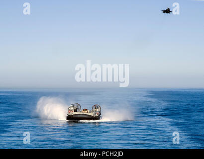 Pazifik (Okt. 2010) 24, 2017) eine Landing Craft, Luftgepolsterte (LCAC) vom Angriff Craft Unit (ACU) 5 Ansätze der gut Deck des Wasp-Klasse amphibisches Schiff USS Essex (LHD2) als F-35B Blitz II Flugzeuge zu den "Wake Island Avengers" der Marine Fighter Attack Squadron (Vmfa) 211 Overhead während der Dämmerung Blitz 2017 fliegt zugeordnet. Dawn Blitz ist ein szenario-driven konzipiert und Navy und Marine Corps Einheiten, indem eine stabile Schulungsumgebung wo Kräfte planen und einen amphibischen Angriff ausführen zu integrieren, engagieren sich im Live-Ereignisse und die expeditionary Vorteil Stockfoto