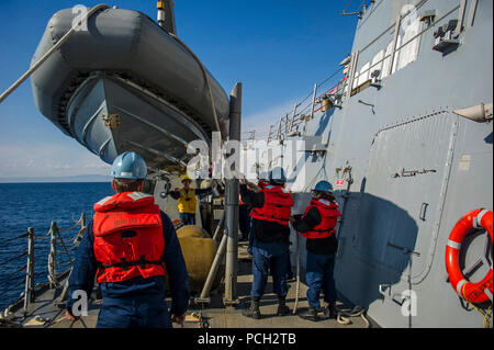 Westlichen PAZIFISCHEN OZEAN (Jan. 17, 2014) der Bootsmann Mate 3. Klasse Paul Landsittel, Mitte, von Jacksonville, Fla., Signale Segler aus der geführten Anti-raketen-Zerstörer USS McCampbell (DDG85) zu einem starren - Rumpf Schlauchboot (Rhib) an einer Dockingstation Senken nach einer Mann-über-Bord-Notruf bohren Sie an Bord des Schiffes. McCampbell ist auf Patrouille in der Siebten Flotte Bereich der Maßnahmen zur Förderung der Sicherheit und der Stabilität in der Indo-Asia-Pazifik-Region. Stockfoto