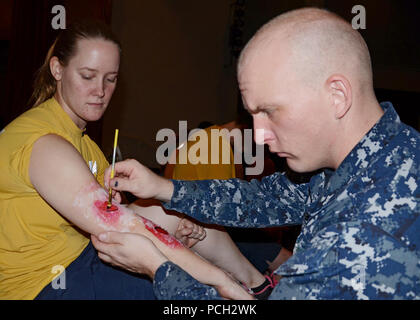 SANTA Rita, Guam (Nov. 8, 2012) Hospital Corpsman 2. Klasse David Haynesnorton, U.S. Naval Hospital Guam zugeordnet, gilt fake Narben an Maschinen Handwerker 3. Klasse Terri Marcum, zum U-Boot Tender USS Frank Kabel zugewiesen (40), für eine Mass Casualty Übung. Stockfoto