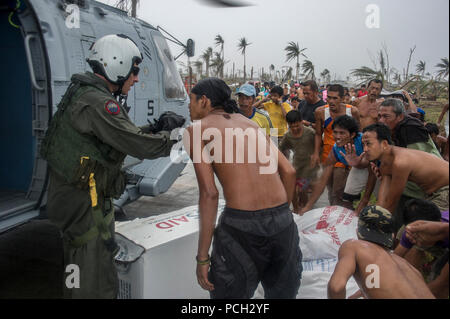 HENANE, Provinz Eastern Samar, die Republik der Philippinen (Nov. 17, 2013) Naval Aircrewman (taktische Hubschrauber) 1. Klasse Logan Robertson, links, von Marianna Fla., spricht mit philippinischen Zivilisten nach ihren Hilfsfluegen in ihrem Dorf während des Betriebs Damayan. Die George Washington Carrier Strike Group in Abstimmung mit den 3d-Marine Expeditionary Brigade ist die Unterstützung der philippinischen Regierung in laufenden Hilfsmaßnahmen in Reaktion auf die Folgen der Super Typhoon Haiyan/Yolanda in der Republik der Philippinen. Stockfoto