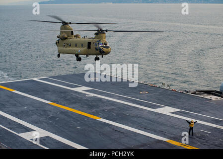 PUGET SOUND (31. 18, 2016) ein Seemann leitet ein CH-47 Chinook mit dem Washington National Guard für die Landung an Bord des Flugzeugträgers USS John C Stennis (CVN 74) Während deck Landung Qualifikationen zugewiesen. Deck Landung Qualifikationen ermöglichen Hubschrauberpiloten proficiency Landung an Bord von Schiffen zu gewinnen. John C Stennis ist unterwegs Routine Ausbildung in der dritten Flotte Verantwortungsbereich durchzuführen. Stockfoto