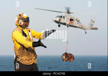 Golf von OMAN (5. Februar 2014) Luftfahrt Boatswain Mate (Handling) 1. Klasse Ruben Anderson leitet Flugverkehr während ein MH-60 s Sea Hawk Hubschrauber zugewiesen der "Ritter des Meeres" der Hubschrauber Meer bekämpfen Squadron (HSC) 22 bereitet sich auf Fracht auf dem Flugdeck des Flugzeugträgers USS Harry S. Truman (CVN-75) liefern während Nachschub auf See. Truman, Flaggschiff der Harry S. Truman Carrier Strike Group, wird in den USA bereitgestellt 5. Flotte Aufgabengebiet Gefahrenabwehr Operationen durchführen, unterstützen Theater Sicherheitsbemühungen Zusammenarbeit und Unterstützung der Operation Enduring Stockfoto