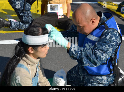 YOKOSUKA, Japan (Nov. 7, 2012) Hospital Corpsman 3. Klasse Dennis Mata, U.S. Naval Hospital Yokosuka zugeordnet, wraps Gaze um den Kopf eines simulierten Patienten während eines bilateralen Mass Casualty Bohrer an Flotte Aktivitäten, Yokosuka. Die Übung vertraut gemacht, US-amerikanischen und japanischen Maritime Self Defense Force Segler mit ihren Verantwortlichkeiten und demonstriert die Interoperabilität bei der Reaktion auf mögliche Mass Casualty Katastrophen. Stockfoto