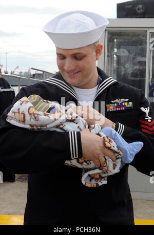 NORFOLK (Nov. 3, 2012) ein Matrose zu den Los Angeles-Klasse Angriffs-U-Boot USS Norfolk (SSN714) hält sein neugeborenes zum ersten Mal während des U-Bootes homecoming Zeremonie an der Naval Station Norfolk. Norfolk reisten mehr als 30.000 Seemeilen während der sechsmonatigen Einsatz und führte port Besuche in Haifa, Israel, Limassol, Zypern; Bahrain und Diego Garcia. U.S. Navy Stockfoto