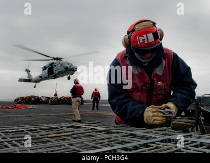 Pazifik (Feb. 18, 2013) Aviation Ordnanceman Airman Gabriel Rubio sichert eine Schlinge Last für den Verkehr auf den Flight Deck während einer Ordnance onload an Bord der Flugzeugträger USS Carl Vinson (CVN 70). Carl Vinson ist unterwegs die Durchführung von Precision Approach Landing System (Kumpel) und Flight Deck Zertifizierungen. Stockfoto