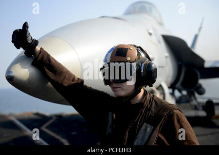 5. US-Flotte VERANTWORTUNGSBEREICH (Jan. 21, 2013) - Aviation Elektriker Mate's 3.Klasse Amanda Walker, von St. Mary's, Ga, signalisiert, dass eine F/A-18C Hornet aus dem goldenen Drachen der Strike Fighter Squadron (VFA) 192 bereit ist sich zu bewegen auf dem Flugdeck der Flugzeugträger USS John C Stennis (CVN 74). John C Stennis ist in die USA 5 Flotte Verantwortungsbereich Durchführung Maritime Security Operations eingesetzt, Theater Sicherheit Bemühungen um Zusammenarbeit und Unterstützung für die Operation Enduring Freedom. Stockfoto