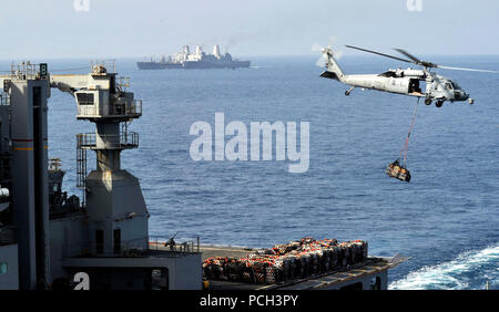 Arabisches Meer (29. März 2014) ein MH-60 s Sea Hawk-Hubschrauber transportiert Ladung Paletten aus der Military Sealift Command Trockenfracht und Munition Schiff USNS Robert E. Peary (T-AKE-5) zum Mehrzweck amphibischer Angriff Schiff USS Bataan (LHD-5) bei einer vertikalen Nachschub. Im Hintergrund führt die amphibischen Transportschiff der Dock USS Mesa Verde (LPD 19) ein Nachschub auf See mit der Flotte Nachschub Öler USNS Joshua Humphreys (T-AO 188). Bataan ist das Flaggschiff für die Bataan amphibische bereit Gruppe und mit der eingeschifften 22. Marine Expeditionary Unit (22. MEU) in Supp bereitgestellt wird Stockfoto