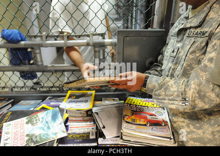 GUANTANAMO BAY auf Kuba – A Soldier aus der Häftling Bibliothek übergibt ein Buch einem Häftlings in fünf Lager 16 Februar.  JTF Guantanamo bietet sichere, humane, legale, transparente Pflege und Obhut der Gefangenen, einschließlich der Militärkommission und die verurteilten freigegeben von einem Gericht angeordnete. Die JTF führt Intelligenzansammlung, Analyse und Verbreitung für den Schutz von Insassen und Personal arbeitet in JTF Guantanamo Einrichtungen und zur Unterstützung des Krieges gegen den Terror. JTF Guantanamo unterstützt Office of Military Commissions, Strafverfolgung und Kriegsverbrechen Untersuchungen Stockfoto