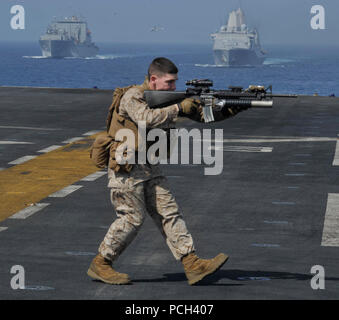 Ein US-Marine mit der 22 Marine Expeditionary Unit (MEU) beteiligt sich an einem Waffen Bohrer auf dem Flugdeck des Amphibious Assault ship USS Bataan (LL 5) im Golf von Aden im März 20, 2014. Die bataan und der 22 MEU waren unterwegs in den USA 5 Flotte Verantwortungsbereich unterstützen Maritime Security Operations und Theater Sicherheit Bemühungen um Zusammenarbeit. Stockfoto