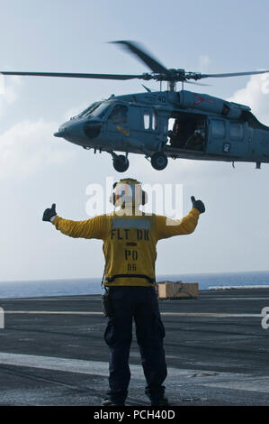 Ein U.S. Navy aircraft Direktor Signale während einer vertikalen Auffüllung auf See mit der schnellen Combat support ship USNS Brücke (T-AOE 10) auf dem Flugdeck der Flugzeugträger USS Carl Vinson (CVN 70) im Pazifischen Ozean Dez. 22, 2011 zu einem MH-60S Knight Hawk mit Helikopter Meer Combat Squadron (HSC) 23. Die Carl Vinson und Carrier Air Wing (Cvw) 17 wurden unter Weg auf einem westlichen Pazifik Bereitstellung. Stockfoto