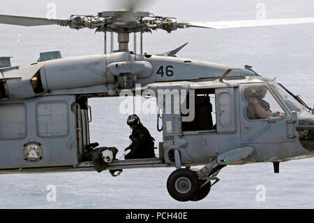 Ein U.S. Navy aircrewman prüft die Cargo Anhänger eines MH-60S Seahawk Helikopter Hubschrauber Meer Combat Squadron (HSC) 23 während einer vertikalen Auffüllung zugewiesen-auf-See zwischen dem schnellen Combat support ship USNS Brücke (T-AOE 10) und amphibische Landung dock Schiff USS Comstock (LSD 45) im Arabischen Golf, 17. Mai 2011. Comstock unterstützt Maritime Security Operations und Theater Sicherheit Zusammenarbeit in den USA 5 Flotte Verantwortungsbereich. Stockfoto