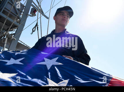 5. US-Flotte EINSATZGEBIET (Feb. 7, 2018) Bootsmann Mate Seemann Austin Schneider hilft eine Schlacht der Stern Falten an Bord der Küstenwache Schiff USS Hurricane (PC3) während der Übung Khunjar Haad. Khunjar Haad ist ein multilaterales, Oberflächen, Luft und die Beseitigung von Explosivstoffen Übung mit der US Navy, US Coast Guard, Royal Navy von Oman, Royal Air Force von Oman, Royal Saudi Seestreitkräfte, die Französische Marine Nationale und in Großbritannien Royal Navy, um die Interoperabilität, die gegenseitige Unterstützung und langfristige regionale Zusammenarbeit der Kräfte, die in den Persischen Golf zu verbessern. Stockfoto