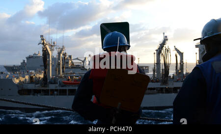 Ein US-Sailor, Mitte, an Bord des amphibious Transport dock Schiff USS Mesa Verde LPD (19) nutzt hand Paddles während einer Auffüll-anforderung auf See im Mittelmeer März 12, 2014 Mit einem nachfüllstation an Bord der Flotte Auffüllung öler USNS John Lenthall (T-AO 189) kommunizieren. Die Mesa Verde war Teil des Bataan amphibischen Bereitschaft Gruppe und war unterwegs in den USA 6 Flotte Verantwortungsbereich unterstützen Maritime Security Operations und Theater Sicherheit Bemühungen um Zusammenarbeit. Stockfoto