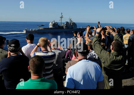 Tiger cruise die Teilnehmer sehen die Ticonderoga-Klasse geführte-missile Cruiser USS Bunker Hill (CG) 52 Wiederherstellen von einem Hubschrauber während einer Luft- und Seemacht Demonstration auf dem Flugdeck an Bord der Nimitz-Klasse Flugzeugträger USS Carl Vinson (CVN 70). Carl Vinson und Carrier Air Wing (Cvw) 17 sind unterwegs auf einem Tiger Cruise nach Abschluss einer Bereitstellung in der 5. und 7. US-Flotte Arbeitsgebiete. Stockfoto