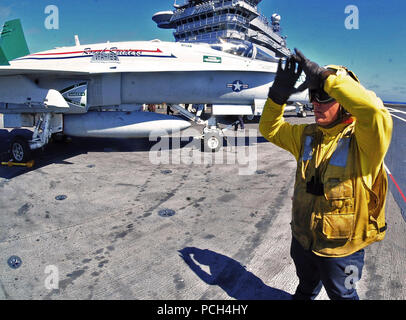 Eine ebene, Direktor der Flugzeugträger USS Carl Vinson zugeordneten Signale einer F/A-18 Super Hornet in Stellung zu bringen. Carl Vinson ist im Gange, die lokale Operationen vor der Küste von Südkalifornien. Stockfoto