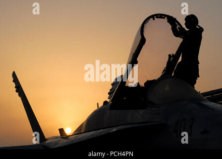 In den Orange glühen der aufgehenden Sonne, Petty Officer 3rd Class Kyle Alhers beginnt die Tage Routine von einem Flugzeug Kapitän, durch Abwischen der Kondensation auf der Überdachung eines F/A-18C Hornet "Faust der Flotte von Strike Fighter Squadron 25 gebildet werden. Ebene Kapitäne sind wichtige Mitglieder der Staffel, sie sind letztlich verantwortlich und stellt sicher, dass Ihre Perspektive Flugzeuge bereit ist, durch die Zeit zu fliegen. Der Nimitz-Klasse Flugzeugträger USS Ronald Reagan ist derzeit auf dem Fünften Flotte/NAVCENT Verantwortungsbereich eingesetzt. Operationen im Bereich der NAVCENT Betrieb Stockfoto