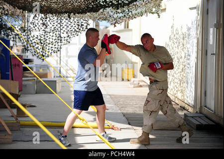 Air Force Staff Sgt. Joshua Sevilla, ein Mechaniker mit dem 81Th Expeditionary Rescue Squadron, feuert einen rechten Jab an einer Hand pad Air Force Staff Sgt. Benson Maiden, auch Mechaniker mit den 81 st, halten Sie während eines cardio Workout außerhalb ihrer Arbeit Platz auf Camp Lemonier, Dschibuti, Okt. 14. Stockfoto