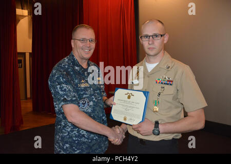 BANGOR, Washington (Sept. 21, 2016) - Kapitän Alan Schrader, Naval Base Kitsap (NBK) kommandierenden Offizier, präsentiert Master-at-Arms 1. Klasse Andrew Duckett mit einer Marine, die Verwirklichung Medaille während alles - Hände Anruf am NBK-Bangor Kino und Theater statt. Mehr als 30 Auszeichnungen und Dekorationen wurden die Segler während der Anlass geschenkt. Es war Schrader das erste All-Hallen Anruf als NBK CO. Stockfoto