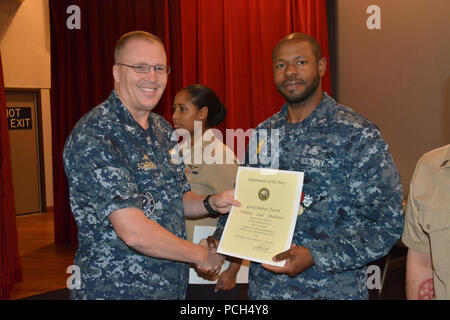 BANGOR, Washington (Sept. 21, 2016) - Kapitän Alan Schrader, Naval Base Kitsap (NBK) kommandierenden Offizier, präsentiert Master-at-Arms 3. Klasse Garris Covington mit einer guten Führung Medaille während alles - Hände Anruf am NBK-Bangor Kino und Theater statt. Mehr als 30 Auszeichnungen und Dekorationen wurden die Segler während der Anlass geschenkt. Es war Schrader das erste All-Hallen Anruf als NBK CO. Stockfoto