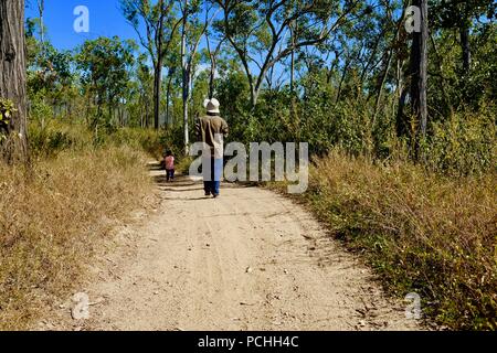 Mann mit einem Kind auf einem trockenen, staubigen Straße durch den Busch, Townsville, Queensland, Australien Stockfoto