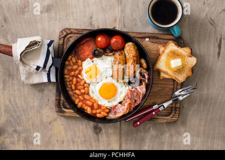 Englisches Frühstück in gusseisernen Pfanne auf Holztisch mit Kopie Raum, Ansicht von oben Stockfoto