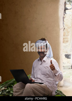 Ländliche Landwirt mit Daumen hoch, während der Arbeit am Laptop Stockfoto