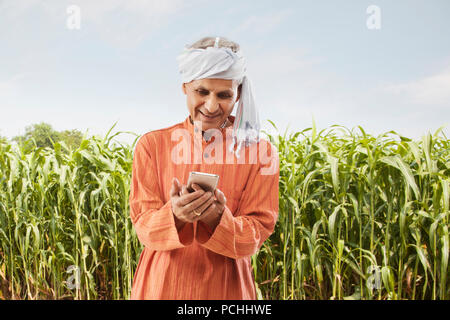 Senior Bauer mit Handy stehen im Feld Stockfoto