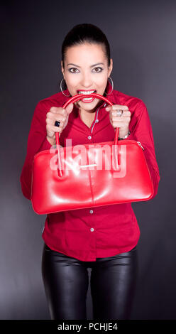 Schöne junge Frau mit roten Beutel in den Zähnen, Studio shot Stockfoto