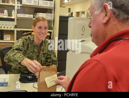 JACKSONVILLE, Fla. (27 Juli 2018) Hospital Corpsman 2. Klasse Jamie Hopkins liefert Medikamente zu Terry Thornhill am Naval Hospital Jacksonville Apotheke. Das Krankenhaus ist die Einführung einer verbesserten Prozess für die Patienten die Medikamente in der Krankenhausapotheke und Sat-Apotheke abholen, in der ab Anfang August. Die Apotheke Check-in Kiosk ermöglicht es Patienten, die durchschnittliche Wartezeit zu sehen, und melden Sie sich Textnachrichten mit Aktualisierungen über den Status ihrer Verschreibung zu erhalten. (U.S. Marine Foto von Jacob Sippel, Naval Hospital Jacksonville/Freigegeben). Stockfoto