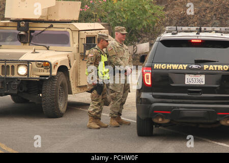 Kalifornien Armee Nationalgarde Sgt. Jesus Valencia und SPC. Cameron Hodges der 270th Military Police Company, 185 Military Police Battalion, 49th Military Police Brigade, eine Shasta County Sheriff 31. Juli am Keswick Damm in Redding, Kalifornien, einem der fast drei Dutzend traffic control points Aktualisieren besetzt von der Militärpolizei auf Ihren ersten Tagen der Aktivierung für die Carr Feuer. (U.S. Army National Guard Foto: Staff Sgt. Eddie Siguenza) Stockfoto