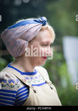 Close-up, Seitenansicht Portrait von isolierten Kriegszeiten Hausfrau, tragen handgestrickte Pullover, Latzhose & Kopftuch im Black Country Museum 1940. Stockfoto