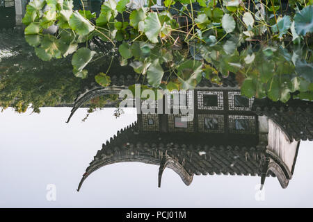 Traditioneller garten Dächer in einem Teich in Suzhou, China wider. Dekorative Skulpturen und Schindeln auf einem alten Gebäude. Stockfoto