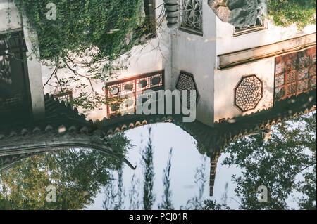 Traditioneller garten Dächer in einem Teich in Suzhou, China wider. Dekorative Skulpturen und Schindeln auf einem alten Gebäude. Stockfoto