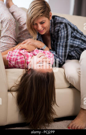 Porträt der jungen schönen Mutter mit ihrer Tochter im Teenageralter auf der Couch zusammen zu spielen und eine gute Zeit Stockfoto